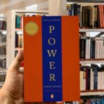 Cover of The 48 Laws of Power by Robert Greene, featuring a bold red and blue vertical split design with gold serif text.