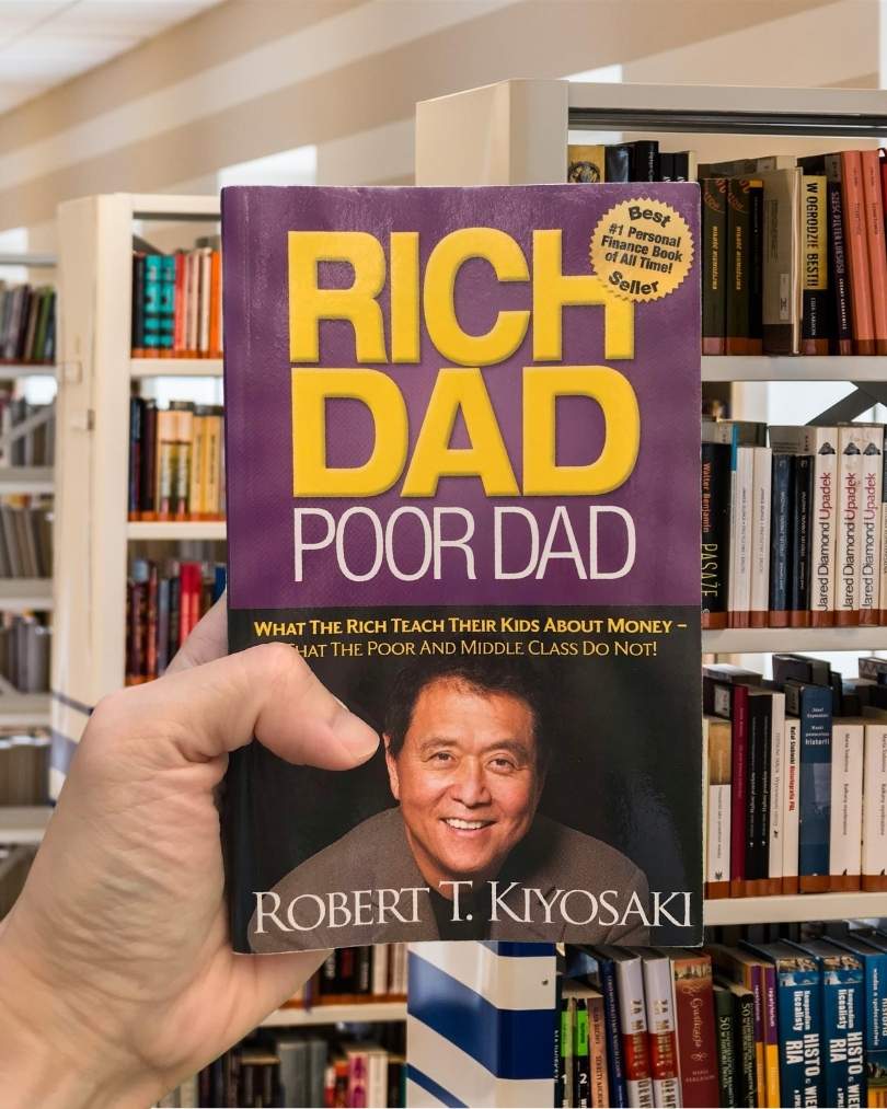 Cover of Rich Dad Poor Dad by Robert Kiyosaki, featuring a purple background, gold text, and a photo of the author.