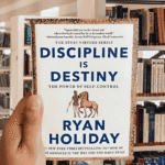 Book cover of "Discipline Is Destiny" by Ryan Holiday featuring a statue with a stoic expression.