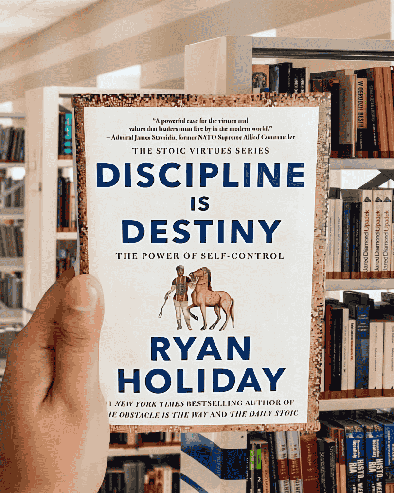 Book cover of "Discipline Is Destiny" by Ryan Holiday featuring a statue with a stoic expression.
