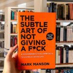 Cover of 'The Subtle Art of Not Giving a F*ck' by Mark Manson with bold orange background and black typography.